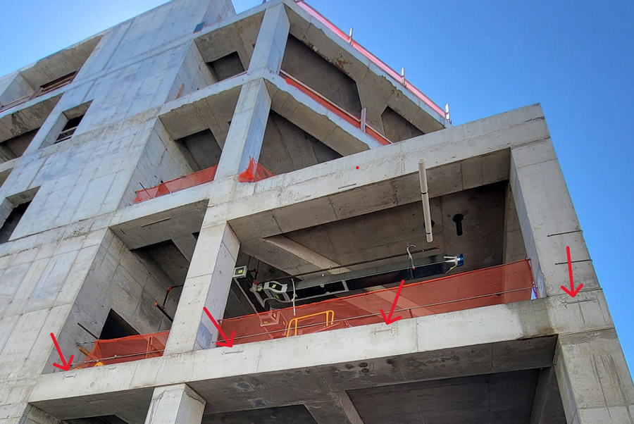 Image 2: Embedded curtain wall anchorage rails (red arrows) were already cast into the PT concrete structure before ICS engaged on the project. The team could not modify these rails or supplement them with post-installed anchorage. Courtesy of KENPAT.
