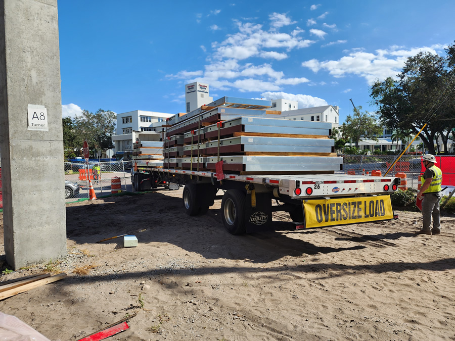 Image 6: A load of prefabricated wall panels arrives at the project site. The team prefabricated hybrid structural donut frames, architectural furring elements that doubled as structural hoisting elements, insulation, sheathing and weatherproofing into the panels for onsite erection. Courtesy of ICS.